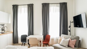 Habitación de hotel con cama, escritorio, silla, sofá y televisión.