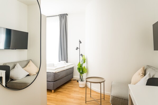 Ein modernes Schlafzimmer mit Bett, Nachttisch und einer Zimmerpflanze.