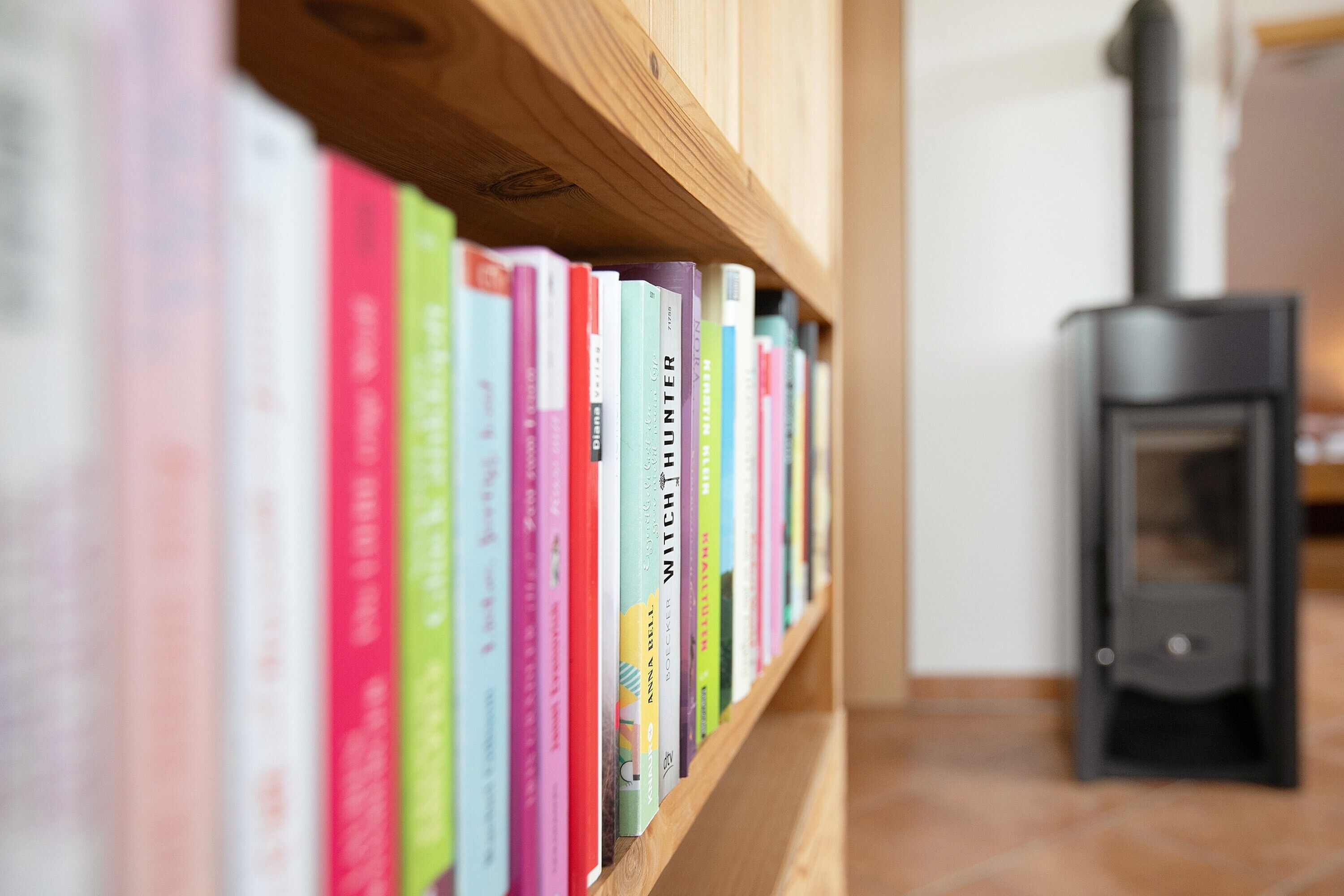 A bookshelf with books and a wood-burning stove in the background.