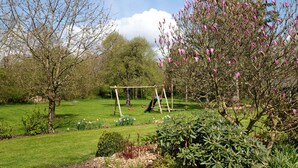 A garden with a swing set, a lawn, and various trees. - Apartment 'Ferienwohnung Coni' with Private Terrace, Private Garden and Wi-Fi (Langballig)
