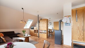 A modern living space with a dining area, kitchen, and a large wooden cabinet. - Apartment 'Ferienwohnung Coni' with Private Terrace, Private Garden and Wi-Fi (Langballig)
