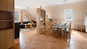 A spacious kitchen with wooden cabinets, a dining table set for four, and a view of the outdoors through a window. - Apartment 'Ferienwohnung Coni' with Private Terrace, Private Garden and Wi-Fi (Langballig)