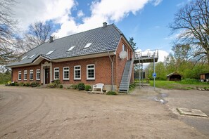 Ein Gebäude aus Backsteinen mit einem geneigten Dach, einer Satellitenschüssel und einer Treppe, die zu einer oberen Ebene führt.
