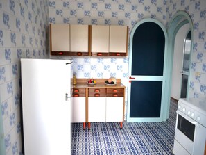 Una cocina con baldosas estampadas, armarios de madera, un refrigerador blanco y una estufa.