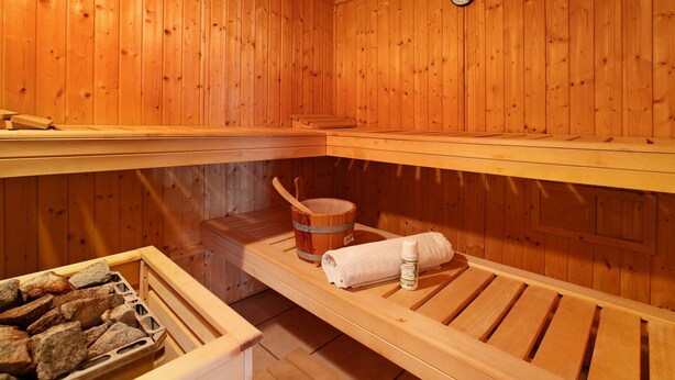 Eine Sauna mit Holzbänken, einem Holzeimer und einem Handtuch.