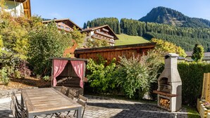 Un espace patio aménagé avec une table et des chaises en bois, un barbecue et un four en pierre.