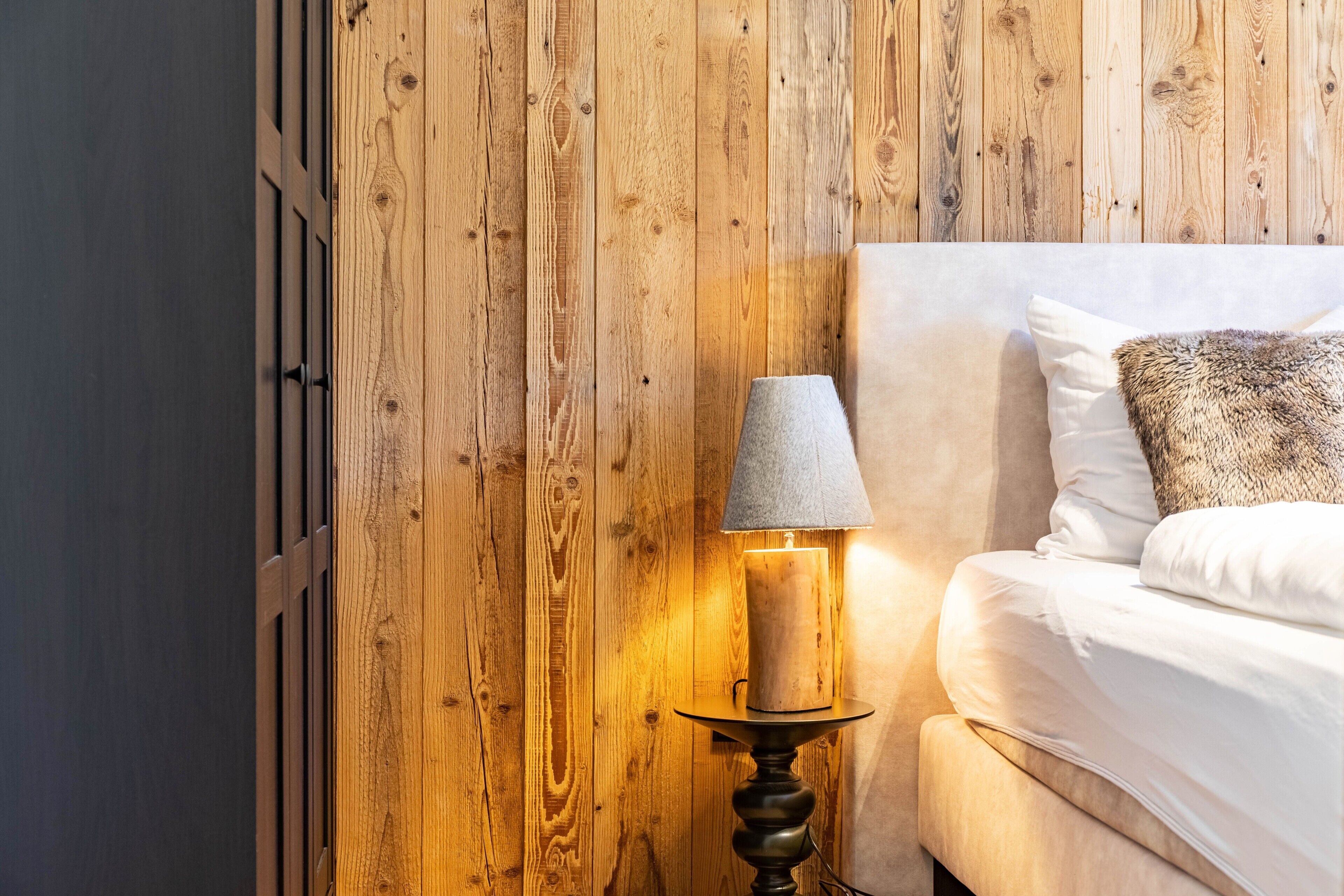 Un mur en bois, une lampe et un lit avec des oreillers.