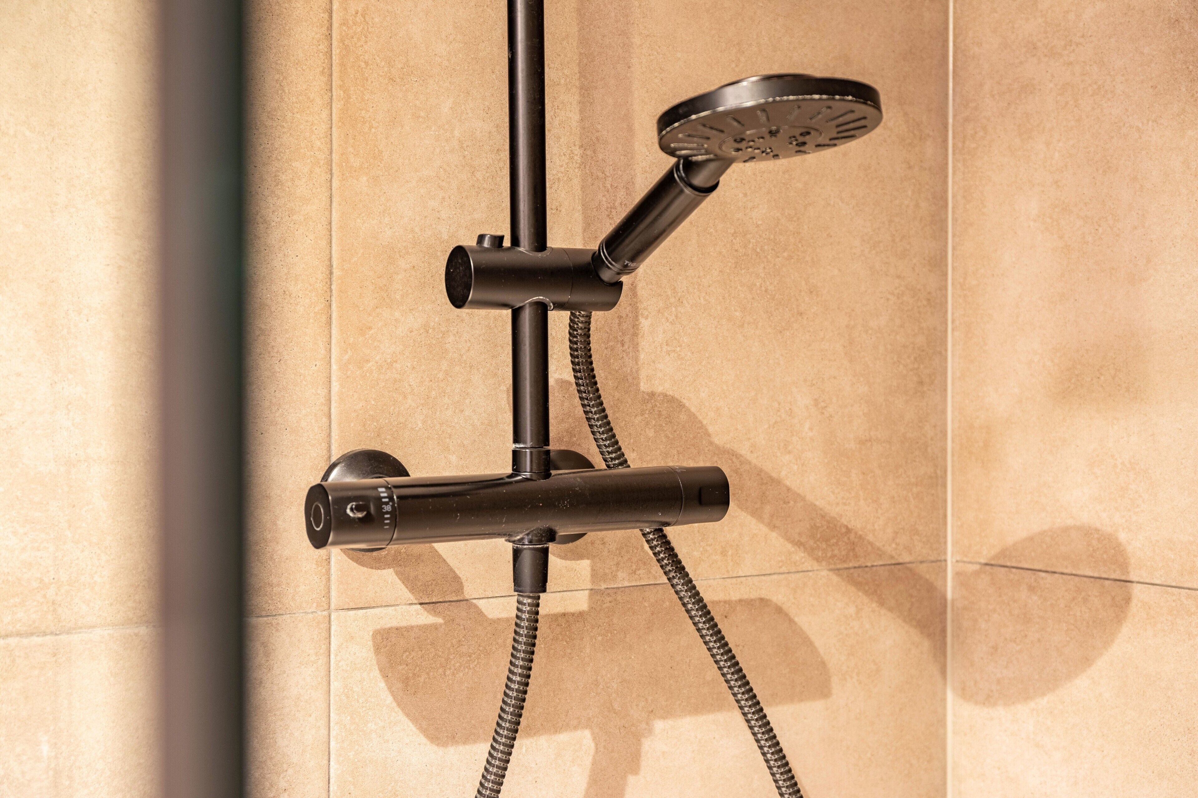 A shower with a handheld showerhead and a fixed wall-mounted showerhead, connected by a flexible hose.