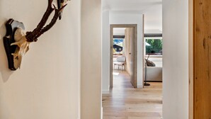 A hallway with a mounted animal head, a wooden door, and a view into a room with a sofa and a lamp.