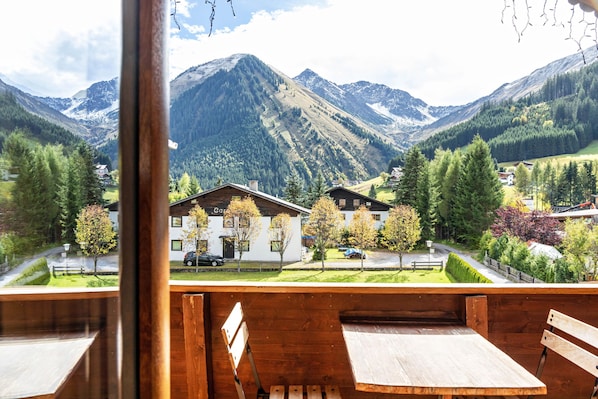 Une vue sur la montagne, avec des bancs en bois et un bâtiment blanc doté d’une cheminée.