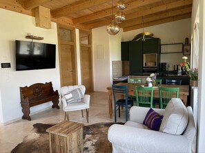 Un salon avec un plafond en bois, une télévision, un banc, un canapé et un coin repas comprenant des chaises et une table.
