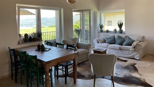 Un vaste espace de vie comprenant une table à manger en bois, des chaises vertes, un canapé blanc et un fauteuil en cuir.