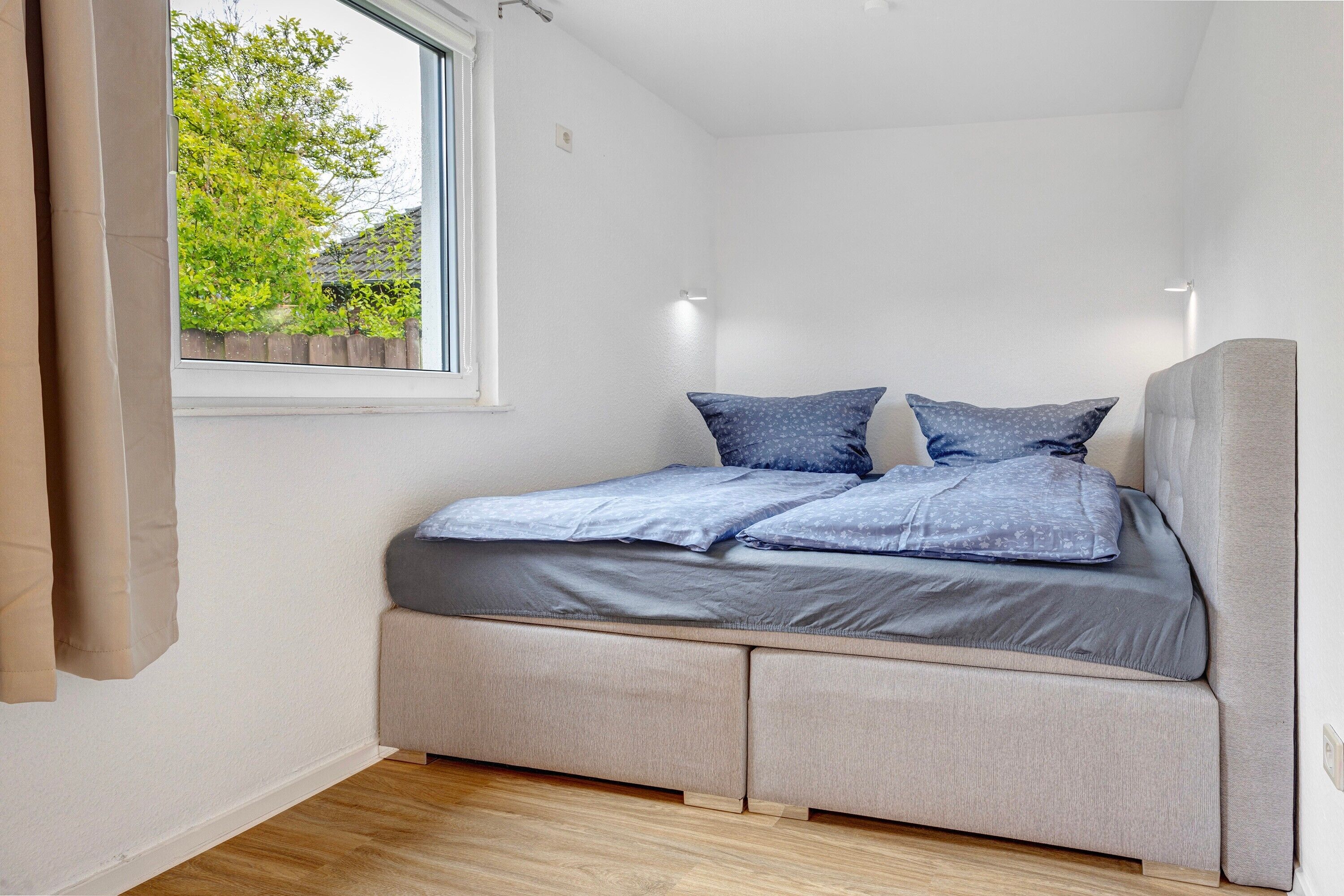 A bedroom with a bed, a window, and a view of greenery outside.