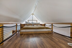 A small, enclosed sleeping area with a bed, wooden flooring, and netted railings. - Holiday Home 'Safarizelt' with Private Terrace, Wi-Fi and Air Conditioning (Großenbrode)
