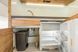 A compact kitchen with a built-in sink, a trash bin, and a refrigerator. - Holiday Home 'Safarizelt' with Private Terrace, Wi-Fi and Air Conditioning (Großenbrode)