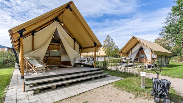 A campsite with two tents, a paved walkway, and a sign indicating the site number. - Holiday Home 'Safarizelt' with Private Terrace, Wi-Fi and Air Conditioning (Großenbrode)