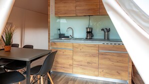 Eine kleine Küche mit Holzausstattung, einer Kaffeemaschine und einem Spülbecken.
