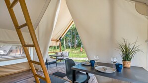 A tented accommodation with a dining area, a ladder, and a view of the outdoors. - Holiday Home 'Safarizelt' with Private Terrace, Wi-Fi and Air Conditioning (Großenbrode)
