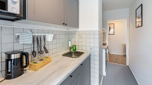 Een keuken met een waterkoker, gootsteen en een houten doos op het aanrecht.