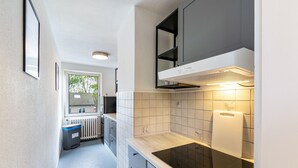 Een moderne keuken met een ingebouwde kookplaat, witte tegels en een raam dat voor natuurlijk licht zorgt.