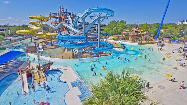 A water park with multiple slides and pools, a beach area with sun loungers, and a large ship-themed structure. - Private Hill Country Pool Retreat w/ Skyline Views (Canyon Lake)