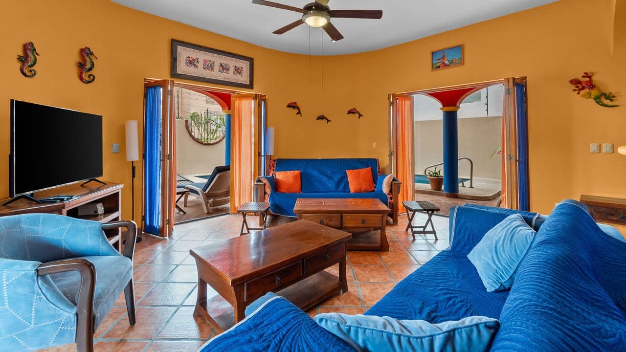 A living room with a blue sofa, a television, and a ceiling fan.