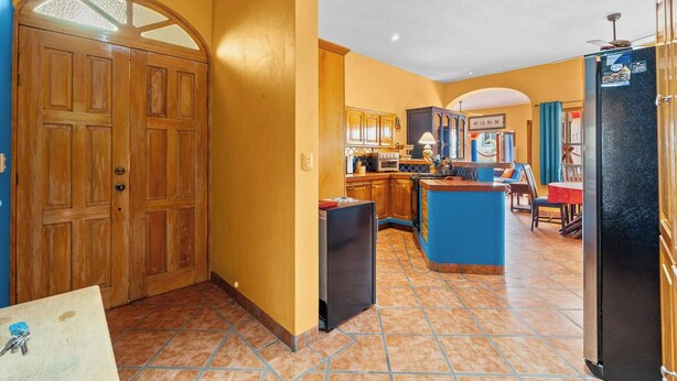 Eine Küche mit Holzausstattung, einem schwarzen Kühlschrank und einer blauen Kücheninsel.