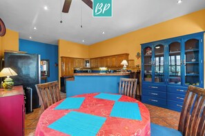 Een keuken met houten kastjes, een blauwe kast met glazen deuren en een tafelkleed in rood en blauw.
