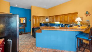 Eine Küche mit blauer Arbeitsplatte, Holzschränken und einer gefliesten Spritzschutzecke.