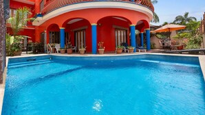 A swimming pool with a red building in the background. - Golden Zone 5 Blocks to Beach - Groundfloor w Pool (Bucerías)