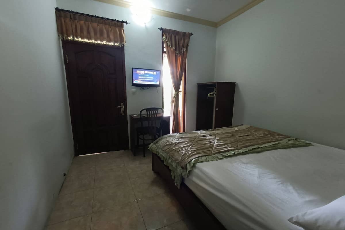 A bedroom with a bed, a desk with a chair, a television, and a wardrobe.