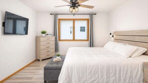 A bedroom with a bed, a dresser, a TV, a ceiling fan, and a window with curtains. - Stylish Townhouse w/ Patio & Free Parking (Appleton)