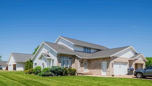 A two-story residential house with a front yard, garage, and a parked car. - Stylish Townhouse w/ Patio & Free Parking (Appleton)