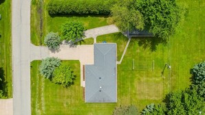 Vista aerea di un edificio con tetto piano, circondato da prati curati e alberi.