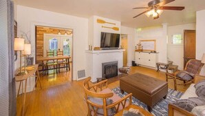 A spacious living room with a fireplace, wooden furniture, and a ceiling fan. - Remodeled Home Steps from Lawrence University (Appleton)