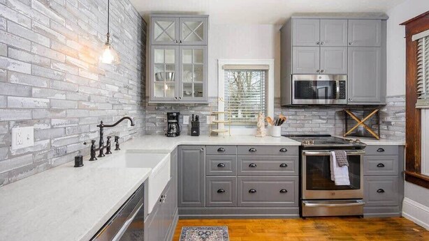A modern kitchen with grey cabinets, a stainless steel oven, and a built-in microwave. - Family-Friendly Home Near Downtown & University (Appleton)