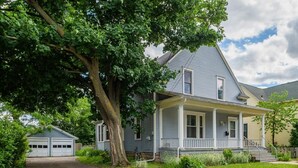 A two-story house with a porch, a garage, and a large tree in front. - Family-Friendly Home Near Downtown & University (Appleton)