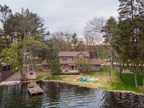 Une maison au bord d’un lac, avec des kayaks, une jetée et un petit abri de jardin.