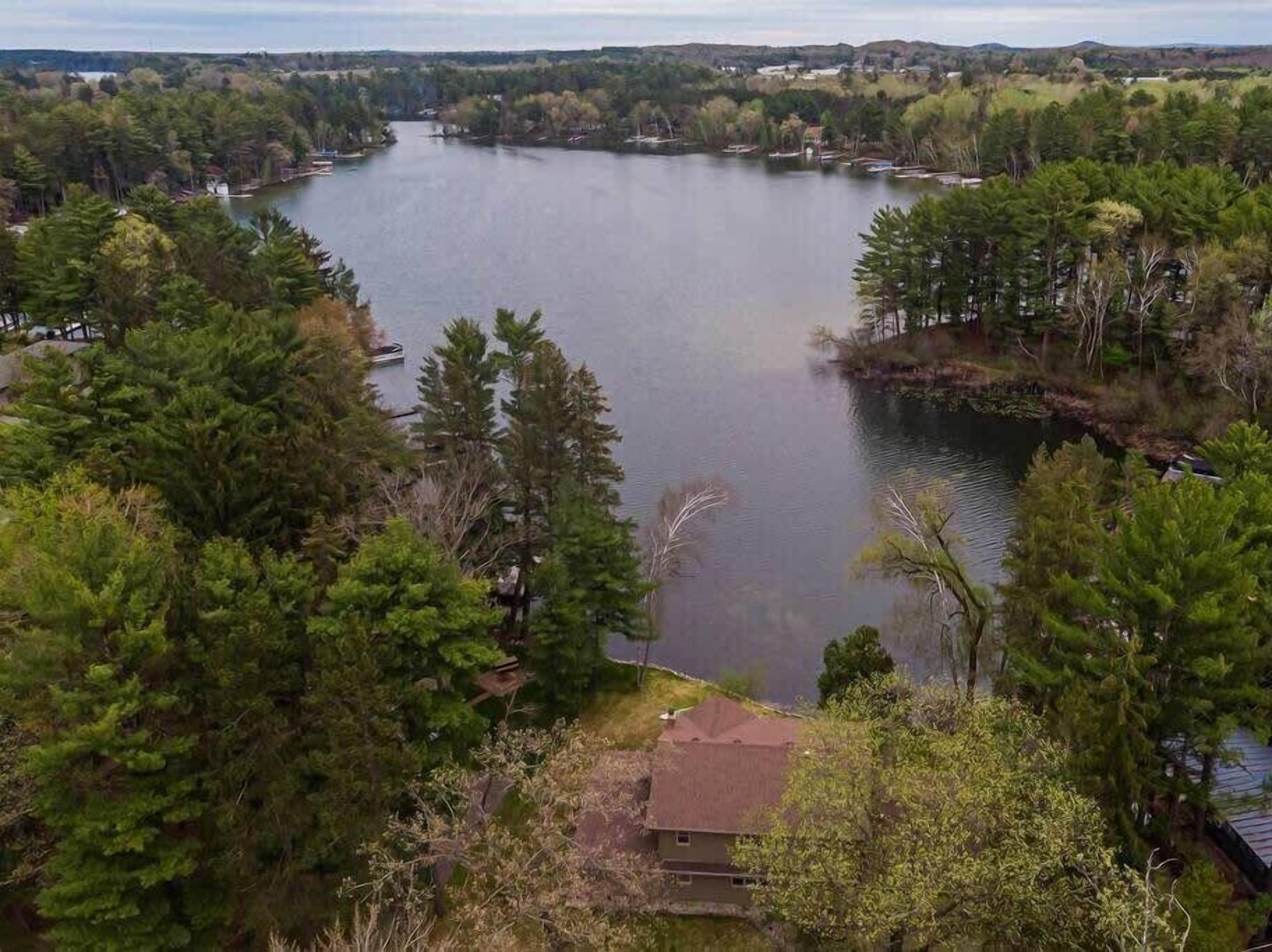 A lake surrounded by dense trees and a small building near the shore.