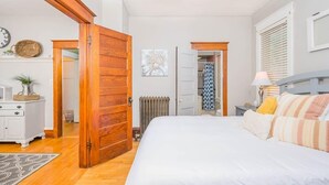 Een slaapkamer met een groot bed, een houten deur, witte muren en een radiator.