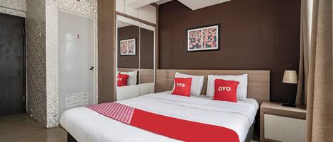 Una habitación de hotel con una cama grande, una mesita de noche, un espejo y una puerta.