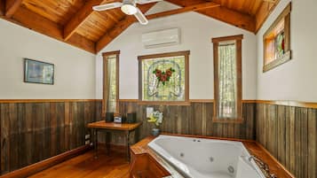 A spacious bathroom with a large bathtub, wooden walls, and stained glass windows.