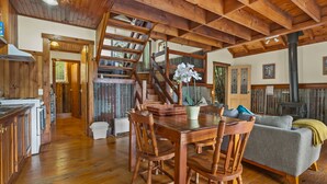 A wooden interior with a dining table, chairs, a sofa, and a staircase. - StayAU 1BR Rustic Picturesque Cottage (Badger Creek)