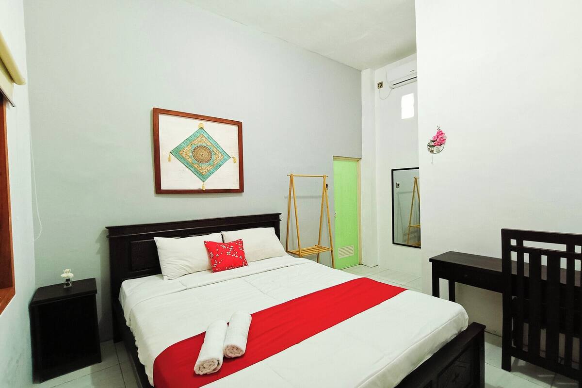 A neatly arranged bedroom with a bed, bedside tables, a desk, and a chair.