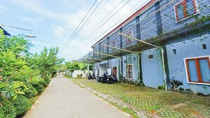 A narrow pathway flanked by buildings with a blue exterior and red window frames. - Hotel O Ipeda Family Residence (Banyuwangi)