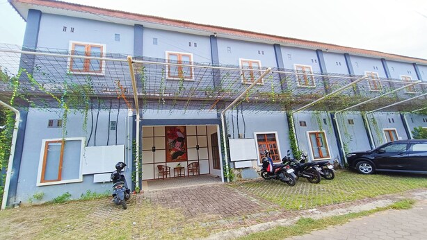 A building with a covered entrance, a car parked outside, and several motorcycles. - Hotel O Ipeda Family Residence (Banyuwangi)