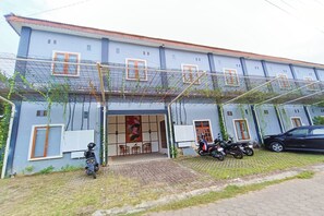 A building with a covered entrance, a car parked outside, and several motorcycles. - Hotel O Ipeda Family Residence (Banyuwangi)