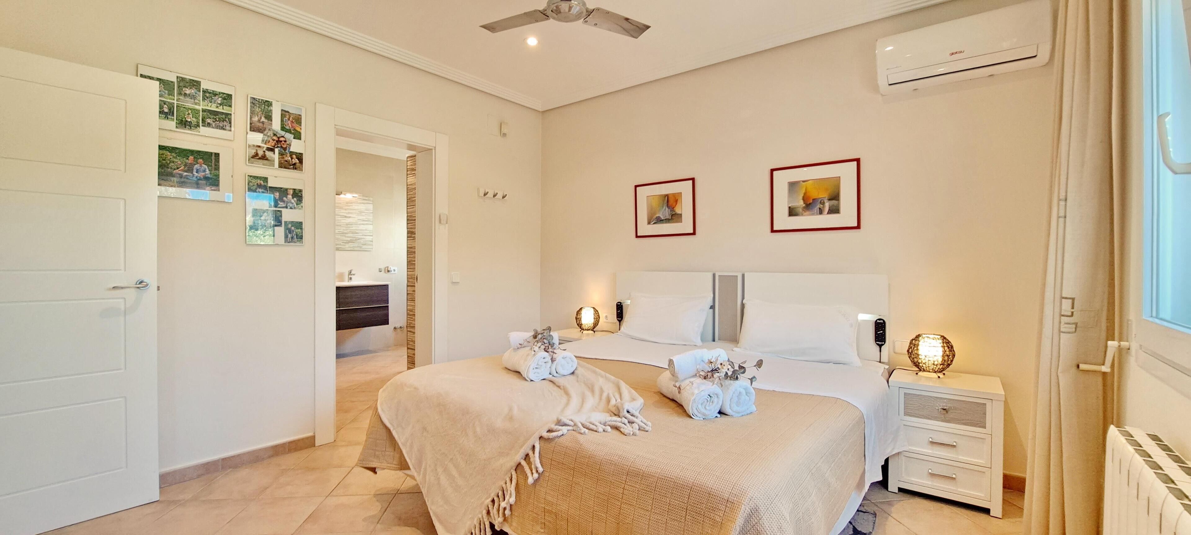 Ein Schlafzimmer mit Bett, Nachttischen, Ablagefläche und Deckenventilator sowie einem Fenster.