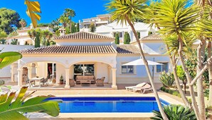 A Mediterranean-style villa with a swimming pool, outdoor seating, and lush tropical plants. - Villa Sollero by Solidays - Moraira, Costa Blanca (Moraira)