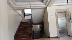 Una escalera que sube a un piso superior, un ascensor y un cartel que indica que el ascensor está fuera de servicio.